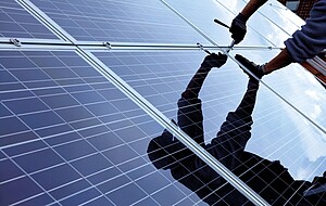 Mann beim Montieren einer Photovoltaikanlage