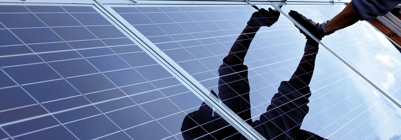 Mann beim Montieren einer Photovoltaikanlage