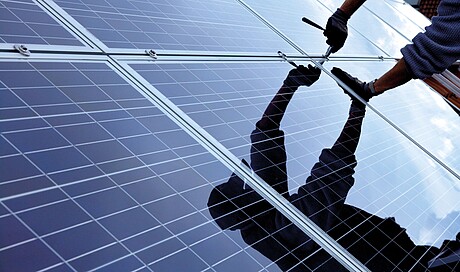 Mann beim Montieren einer Photovoltaikanlage