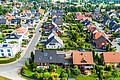 Typical German new housing development in the flat countryside of northern Germany between a forest and fields and meadows, made with drone